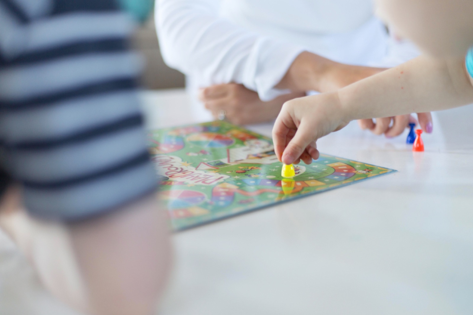 Une main d'adulte et une main d'enfant sur un jeu de plateau